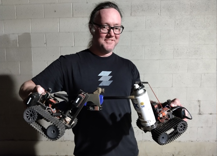 Local hacker and suspected pyromaniac Sodar holding his shoebox sized battle bots named Torchy and Cindy.